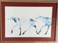 Print featuring two blue-toned horses in motion with a dark red mat and gilded frame, glass covered.