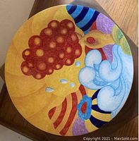 Close-up image of a 14-inch glazed pottery plate showing colorful abstract forms in yellow, red, blue, and white.