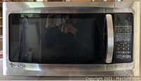 Front view of Magic Chef stainless steel microwave oven with visible control panel and door.