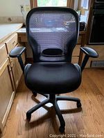 Front view of black ergonomic office swivel chair with mesh back, padded seat, adjustable armrests, and caster wheels.