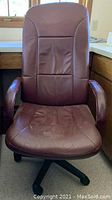 Front view of maroon leather high back swivel office chair showing padded seat, backrest, armrests, and caster wheels.