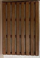 Photo of a slatted teak bathroom mat with horizontally arranged wooden slats and spaces between them.