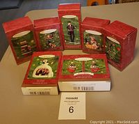 Seven boxed Hallmark Keepsake ornaments arranged on table showing the original packaging and titles on front, including Gouda Reading, Caroler's Best Friend, Harley-Davidson Barbie, Mrs. Claus's Holiday, Tree Guy, Our Family Photo Holder, Close-Knit Friends.