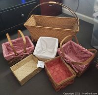 Group photo showing six assorted baskets of various sizes, including large wicker basket with handle, two gingham-lined wooden baskets, and three smaller baskets of different materials and shapes.
