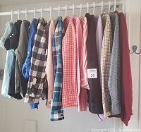 Side view of 15 hanging women's polo shirts and tops in assorted colors and patterns on hangers showing variety of fabrics and styles.