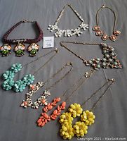 Lot of 7 J.Crew statement necklaces arranged on gray background including floral burst and rhinestone designs