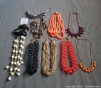 Seven custom statement necklaces laid out on flat surface, showcasing different styles and colors.