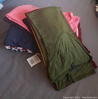 Pile of folded long sleeve shirts in various colors including olive green, pink, black, navy, and red
