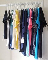 Side view of 16 assorted women's T-shirts on hangers showing various colors and designs