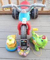 Front view of Thomas & Friends Tough Trike and three colorful educational toys arranged in front