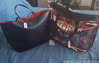 Two tote bags on a bed: left is black Bebe leather tote with red interior, right is pink and silver sequined Victoria's Secret tote with logo text and zipper
