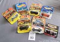 Seven brand new Matchbox and Hot Wheels miniature cars in original sealed packaging shown together flat on surface.