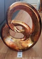 Close-up photo of the abstract modern sculpture table decor with copper, gold and bronze tones, showing the smooth and textured intertwined circular shape.