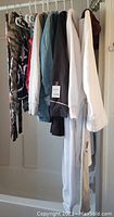11 women's clothing pieces including hoodies, sweaters, and other tops hanging on a rack in multiple colors and styles