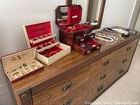 Three jewelry boxes opened and jewelry spread across dresser top