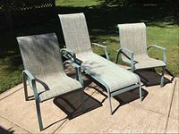 Three outdoor metal framed seating items on patio: one adjustable lounger and two chairs with woven fabric seats.
