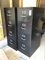 Two black metal HON 4-drawer file cabinets side by side showing front and partial side views with label holders and handles visible.