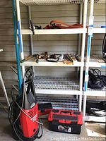 Red Husky pressure washer with trigger gun and hose, red & black plastic toolbox, black tool bag, blue level.