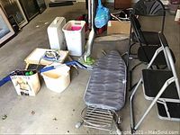 Wide shot showing all items in the lot including chairs, ironing board, mop bucket, floor sweeper, iron, baskets, and fan.