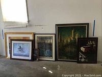 Six pieces of framed wall art displayed on floor leaning against wall