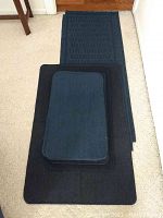 Nine blue rugs arranged on the floor, varying sizes visible from small to runner type