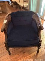Front view of a navy blue upholstered armchair with wood and cane frame, showing the seat and back cushions and the front legs.