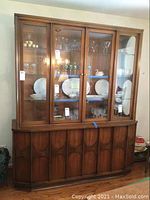 Full front view of the wood china cabinet with glass doors and light inside