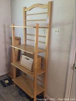 Front view of wood baker's rack showing three shelves and breadbox on middle shelf