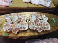 Both wall plaques displayed side by side on furniture surface