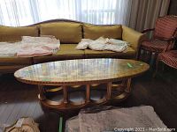 Full view of the oval coffee table positioned in a living room, showing glass top and wood base.