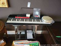Roland CUBE-30 keyboard with stand, tambourine, folk flute and triangle on top, showing overall lot contents
