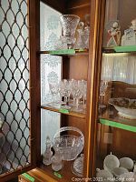Overview of cabinet shelves showing vase, decanters, glasses, basket, cruets, butter dish