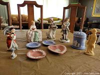 Full view of all figurines and Wedgwood dishes on table showing variety and arrangement in the lot