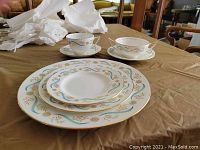Stack of three plate sizes with two cups and saucers on table