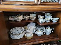 Top shelf: stacks of two-handled soup bowls and tea cups.