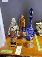 Overview of all items: wood sculpture, two porcelain figurines, crystal decanter and goblets