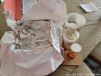 Box with matched set of large teardrop-shaped chandelier crystals, pre-sorted and protected with wrapping paper, visible faceted clear crystals with hanging wires.