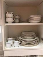 Shelved collection of Paragon fine china: stacked plates, teacups, creamer, and sugar bowl
