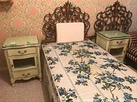 Wide view of the two bedside tables positioned on each side of a bed with ornate headboard, showing the matching design and glass tops.