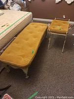 Overall view of bench and stool side by side showing mustard yellow tufted cushions and metal/wood frame with wheels