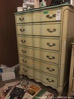 Front view of the ornate six-drawer dresser showing curved drawer fronts, decorative metal pulls, and scratches.