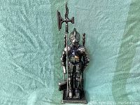 Full view of vintage cast iron suit of armor fireplace tool set with figure holding a pole with axe head and tools in base.