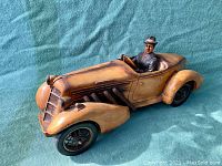 Full side view of the large retro car sculpture with detailed driver figurine and moving wheels.