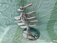 Full view of chrome holder with inserted knives and honing rod on green cloth background