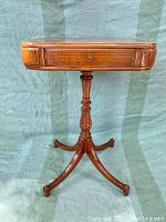 Front view of the vintage side table showing single drawer, turned pedestal and curved legs