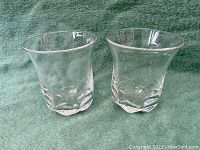 Pair of clear glass Orrefors vases shown side by side on green cloth background.