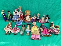 Full collection of 17 vintage world dolls displayed on green fabric background