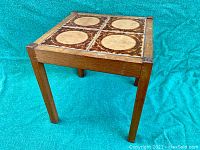 Front angled view of vintage teak tile top table showing the tile pattern and wood frame.