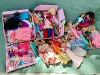 Overall view of numerous Barbie dolls laid out with two boxes of clothing and Barbie Ballet Magnetic Album, showing the extensive collection.