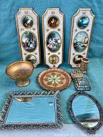 Full lot overview with all items including plaques, mirrors, trays, bowl, and trinket holder visible on blue cloth surface.